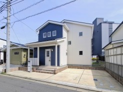 青い屋根と白い外壁のコントラストが印象的な、穏やかな佇まいの住まい。空の広がりを感じさせる整然とした外構は、日常に心地よいリズムをもたらします

