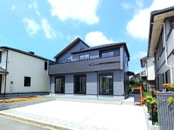 洗練されたダークトーンの外観が空の青さに映え、落ち着いた佇まいと現代的な調和を感じさせる住まいです